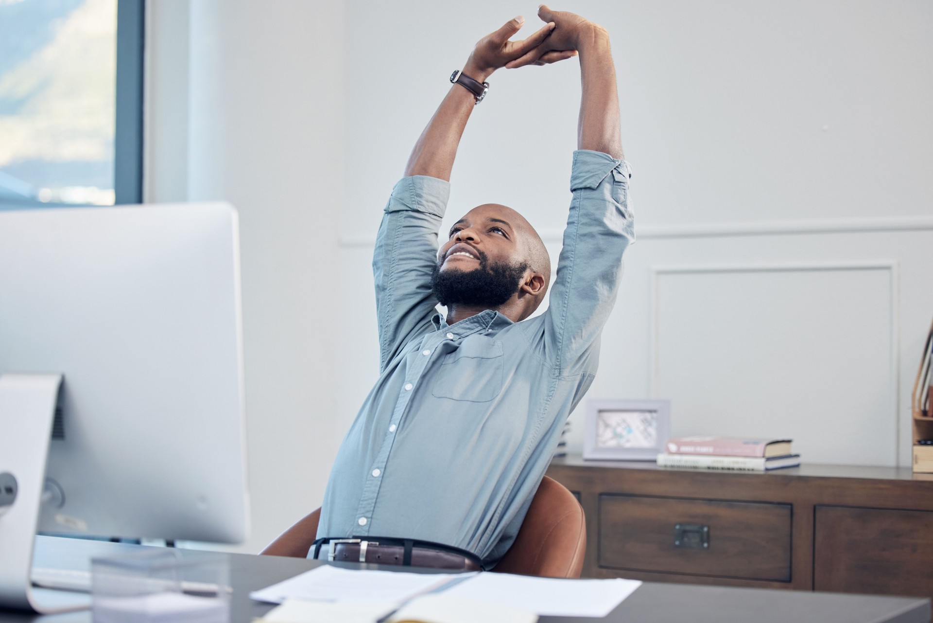 Shot of a handsome young businessman sitting alone in his office and stretching